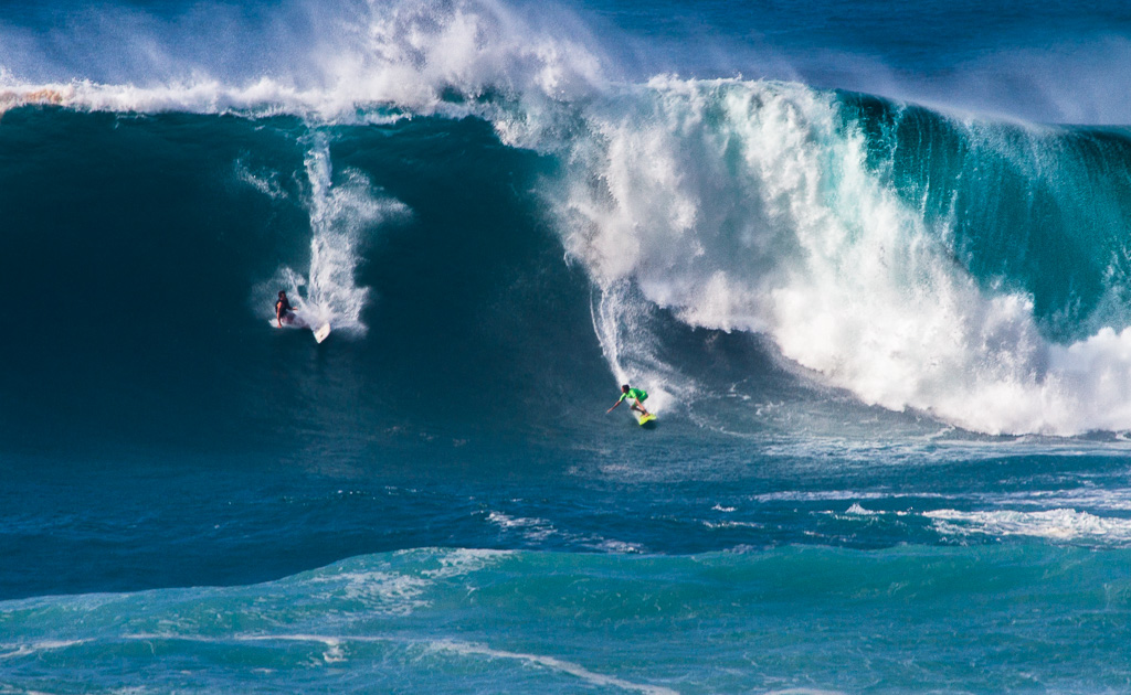 two surfers riding a large wave in the ocean.