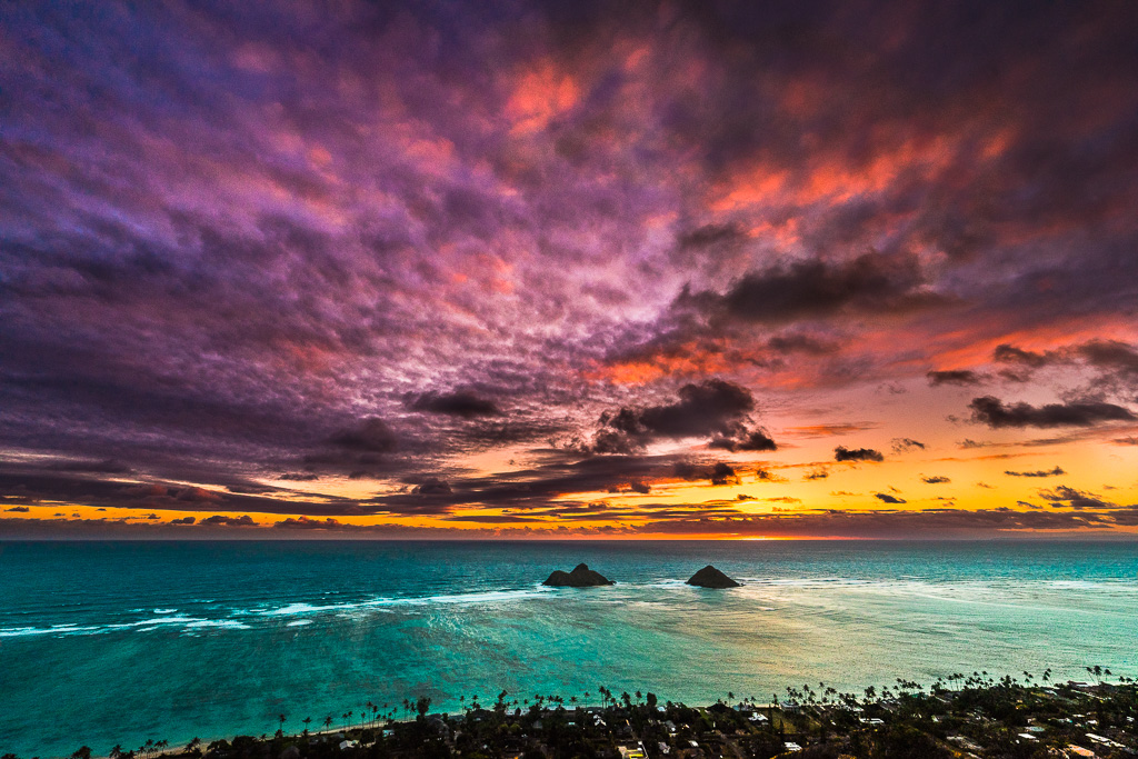 a colorful sunset over the ocean with rocks in the foreground.