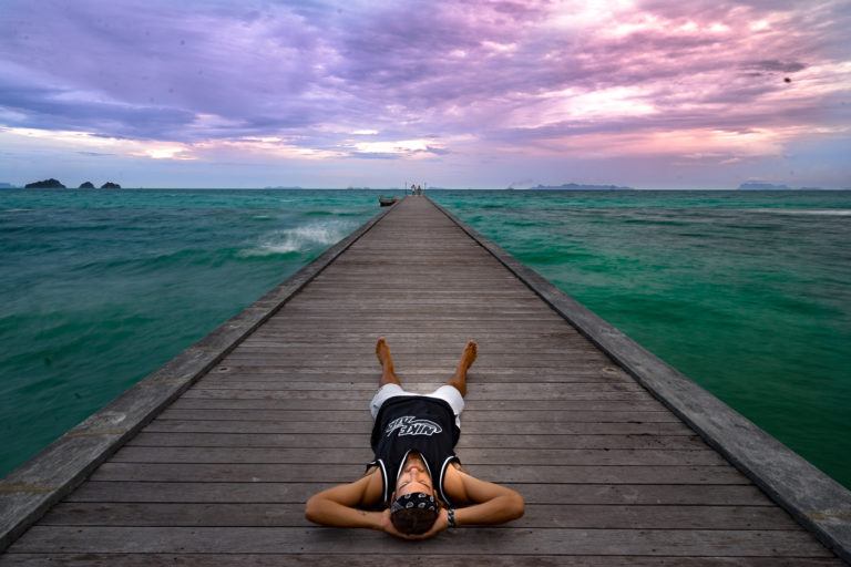 a person laying on a dock in the ocean.