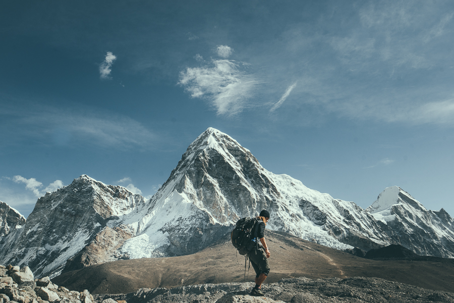 a man standing on top of a mountain with a backpack.
