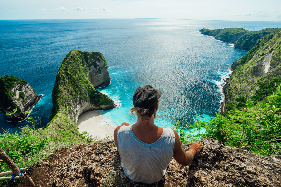 a woman sitting on top of a cliff overlooking a body of water.