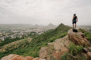 a man standing on top of a mountain with a backpack.