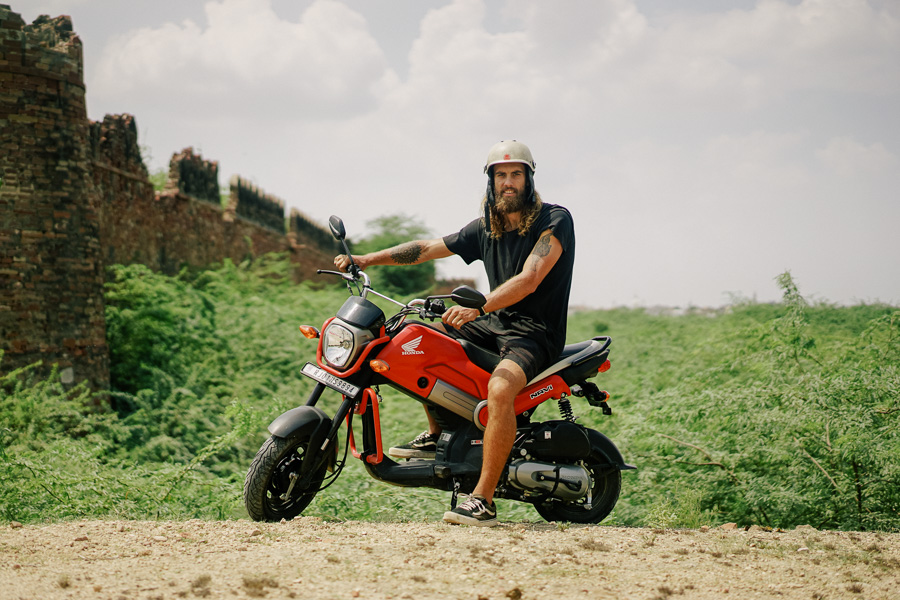 a man riding a red motorcycle down a dirt road.