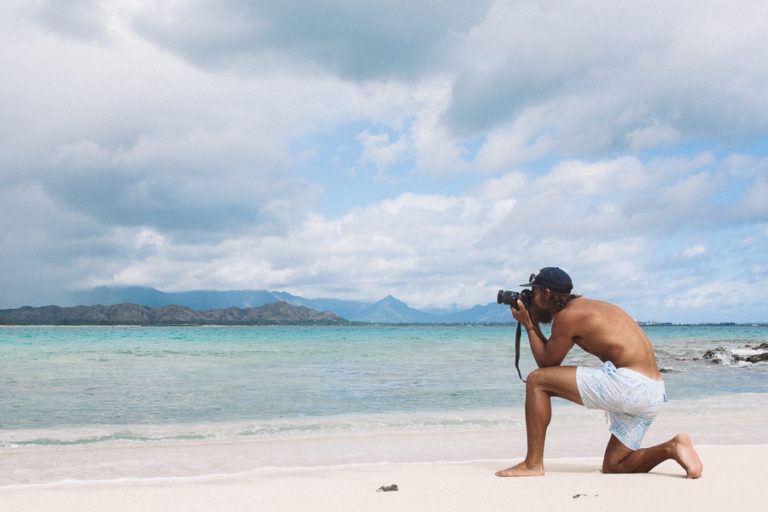 a man taking a picture of a turtle on the beach.