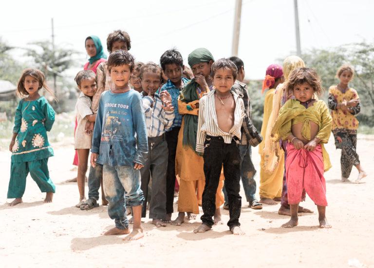 a group of children standing on a dirt road.
