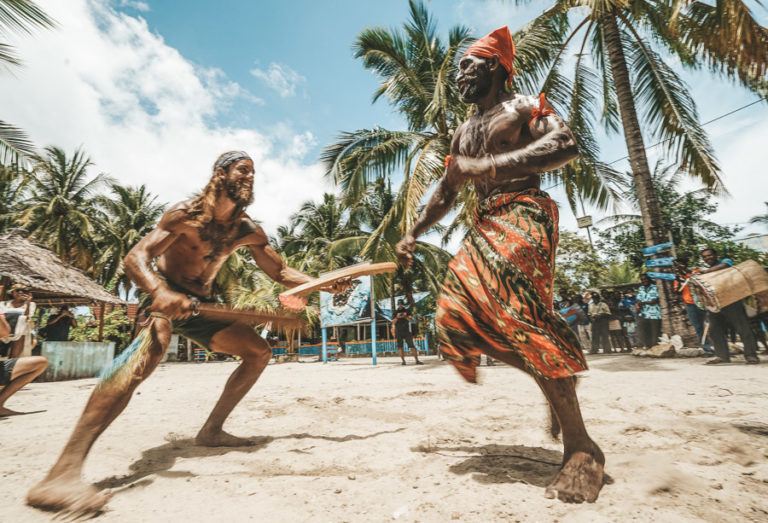 two men playing a game of baseball on the beach.