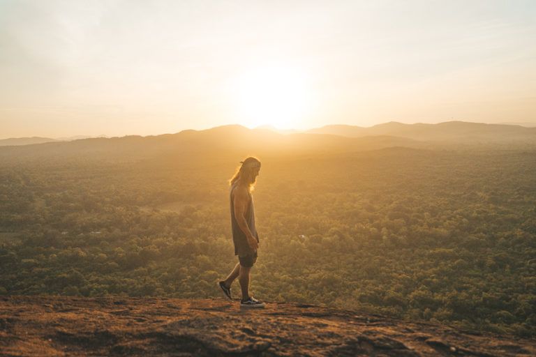a person standing on top of a hill at sunset.