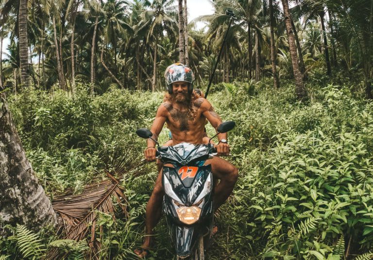 a man riding a motorcycle through a lush green forest.