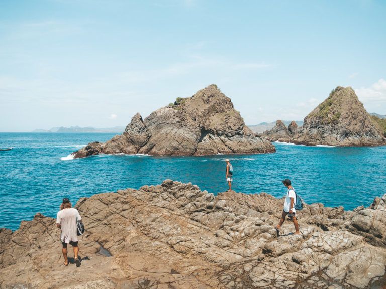 a group of people standing on top of a rocky beach.