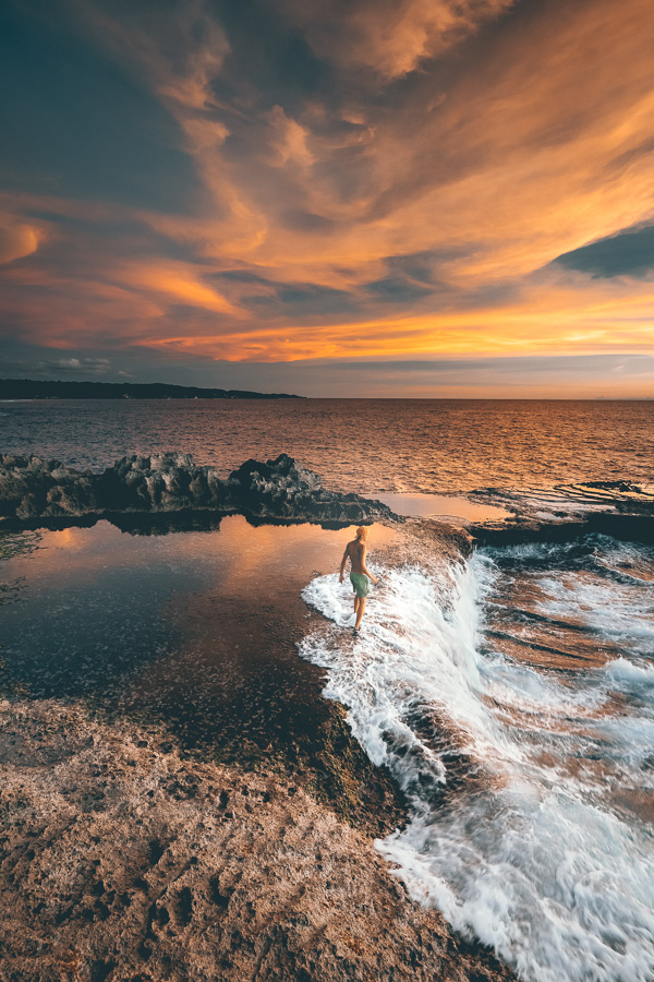 a man is surfing in the ocean at sunset.