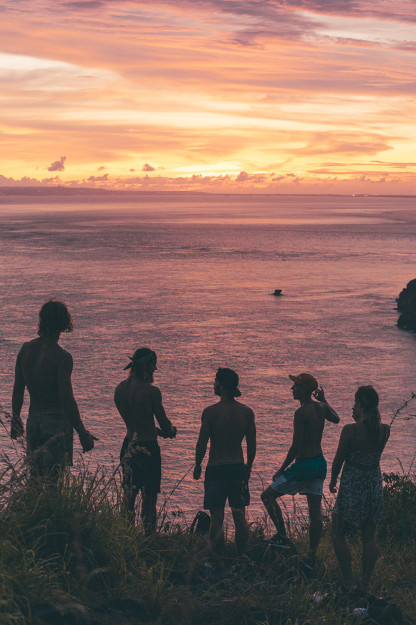 a group of people standing on top of a hill next to the ocean.