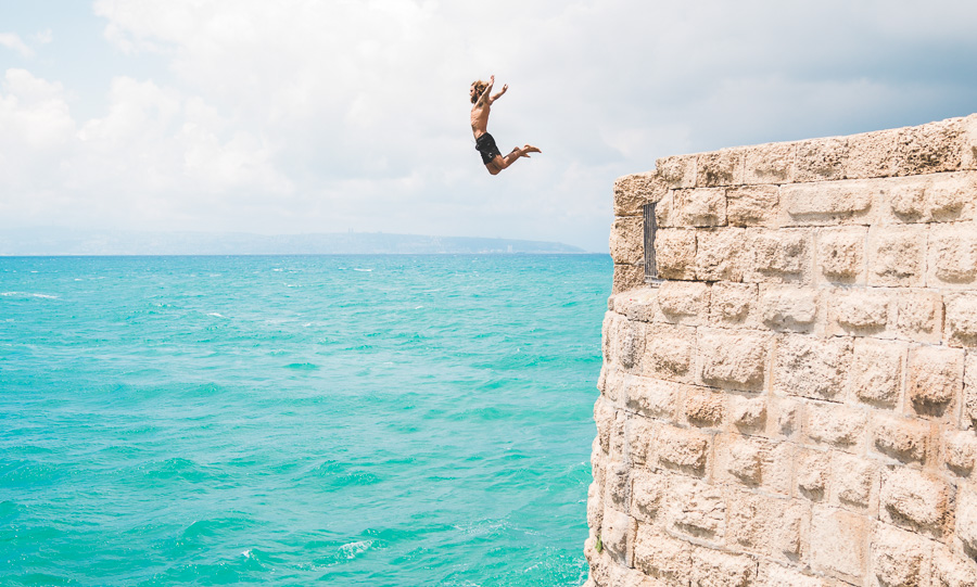 a person jumping off a cliff into the ocean.