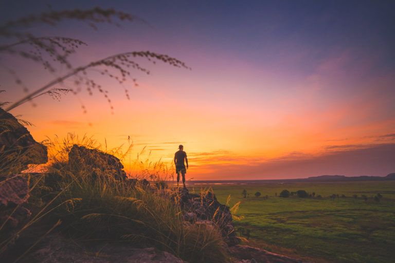 a person standing on top of a hill at sunset.