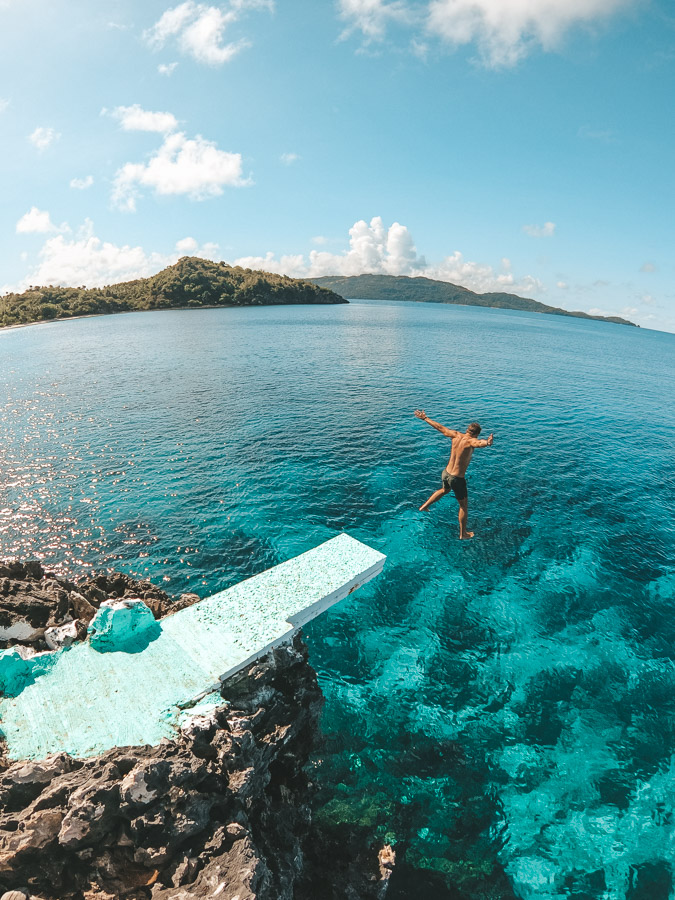 a man jumping off a diving platform into the ocean.