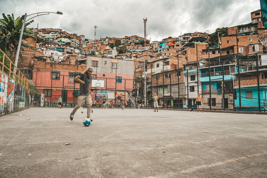 a man kicking a soccer ball on a basketball court.