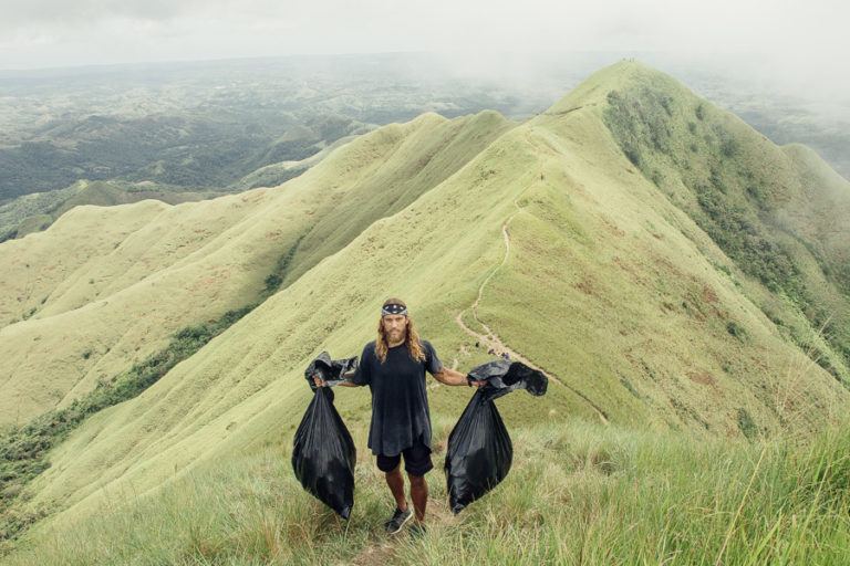 a woman standing on top of a lush green hillside.