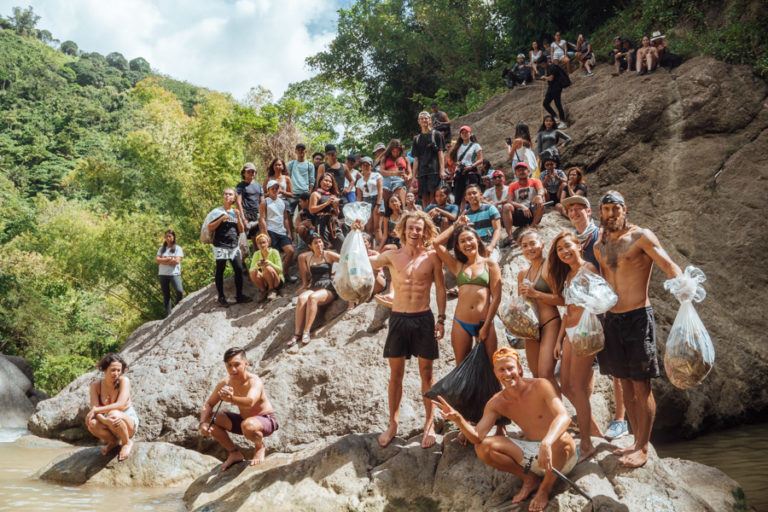 a group of people standing on top of a rock next to a river.