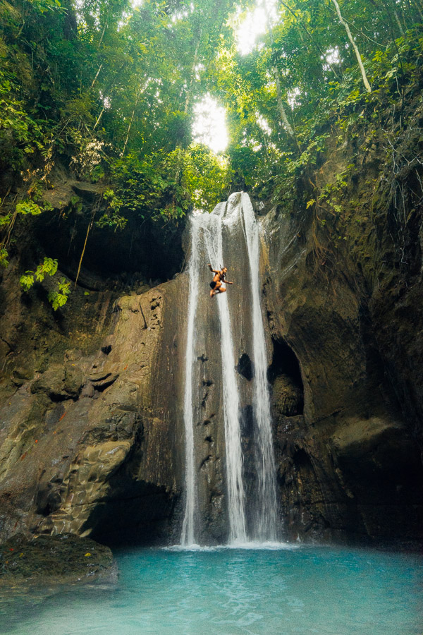 a man is hanging from a rope near a waterfall.