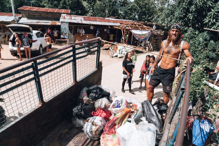a man standing on the back of a truck filled with bags.