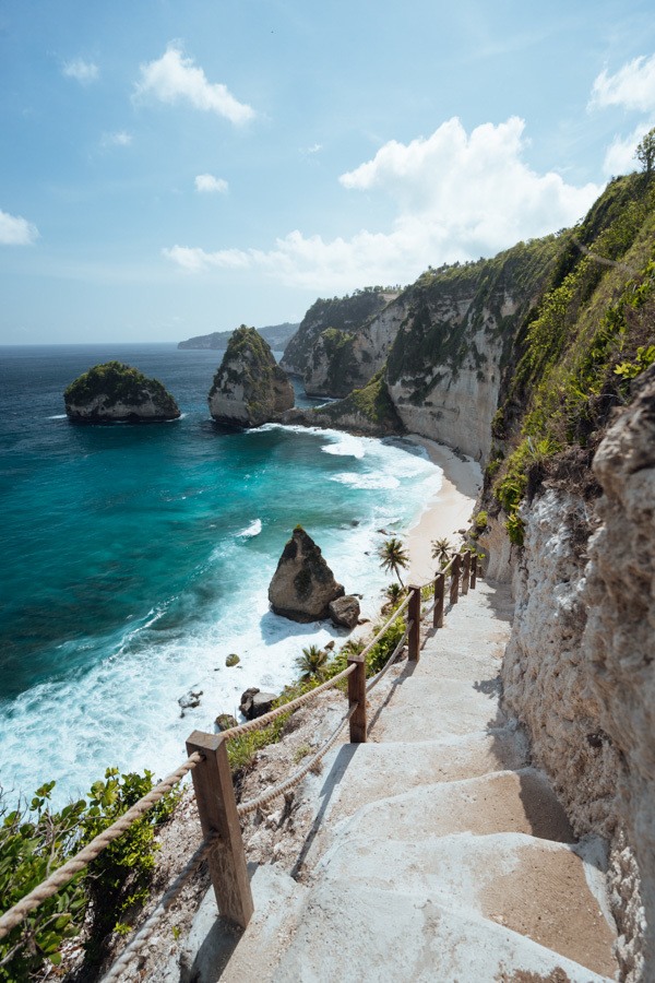 stairs leading down to a beach with a body of water in the background.