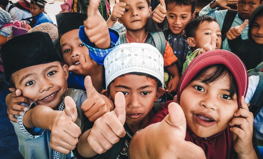 a group of children with their thumbs up.