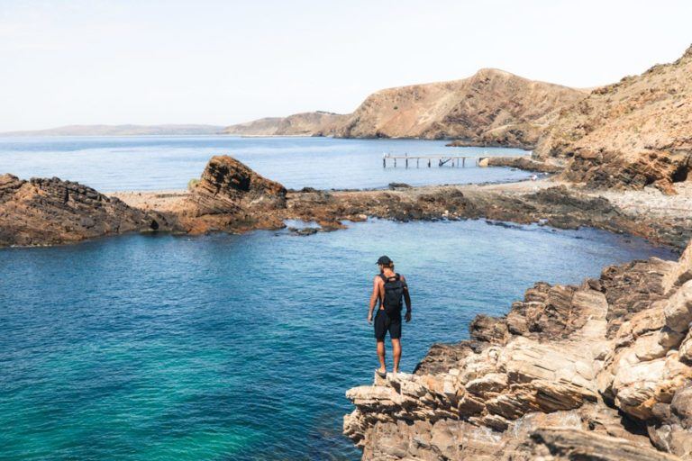 a man standing on the edge of a cliff overlooking a body of water.