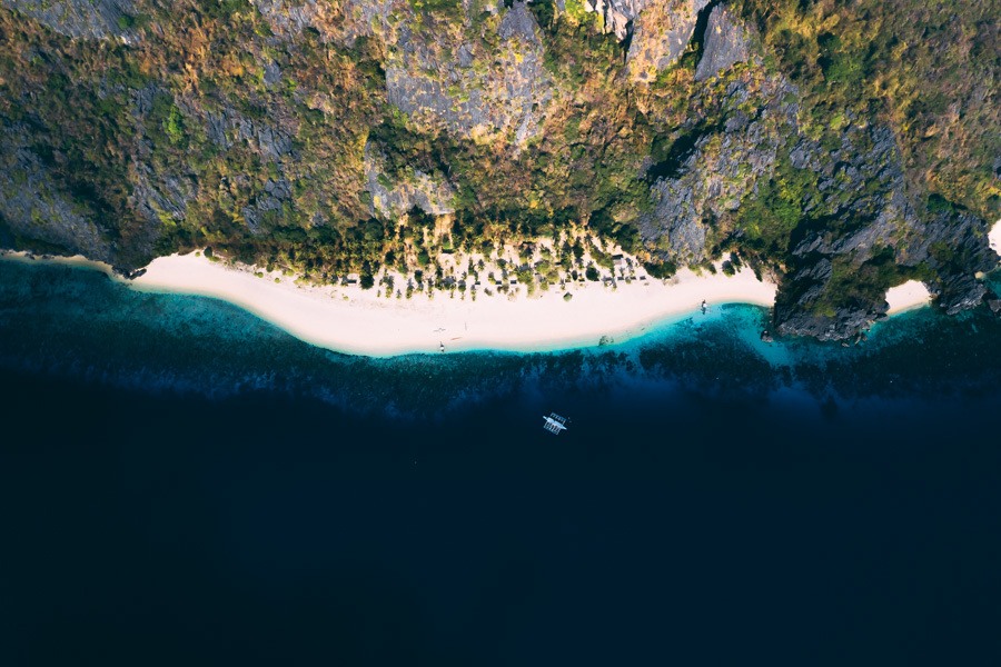 an aerial view of a beach with a boat in the water.