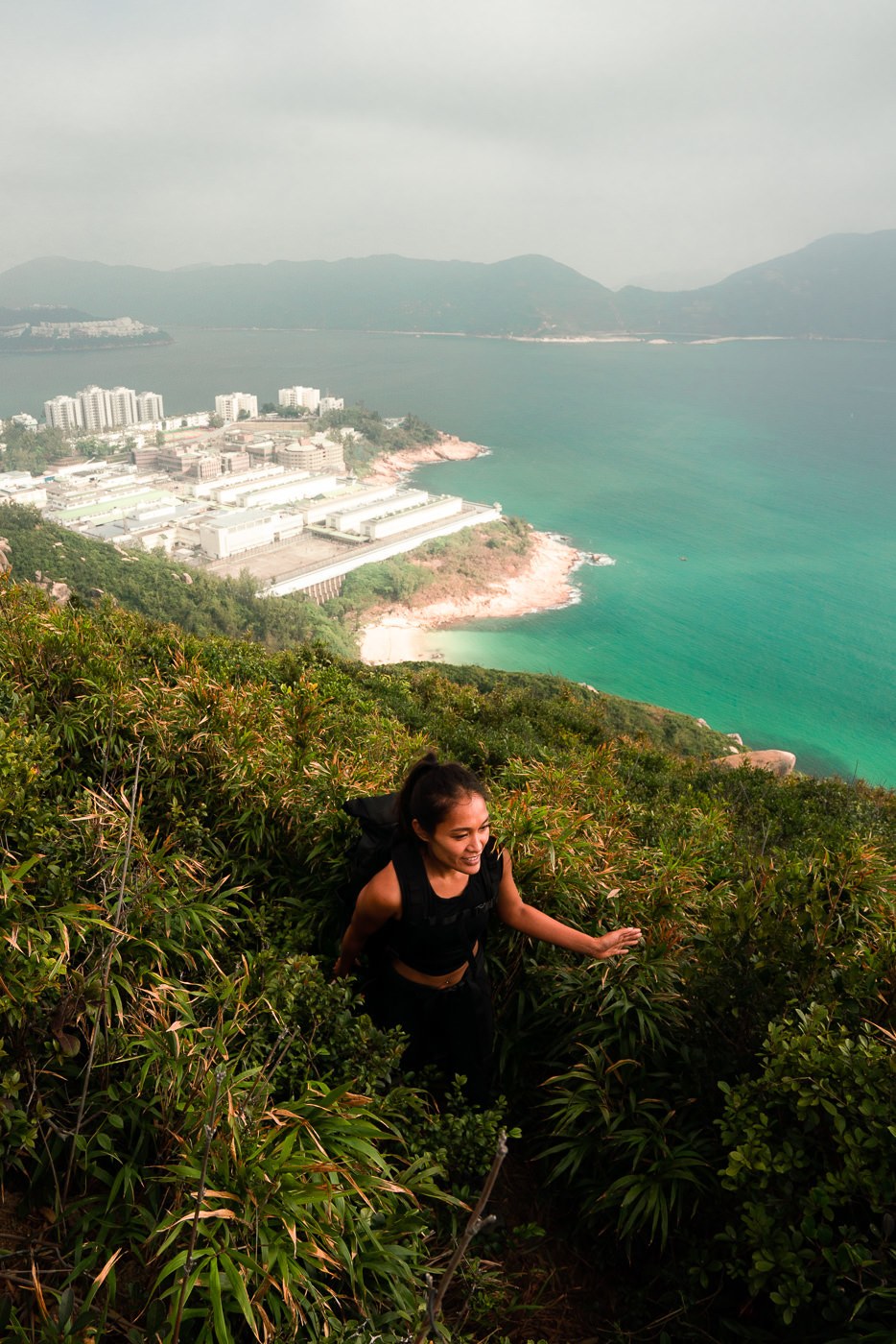 a woman hiking up a steep hill near the ocean.