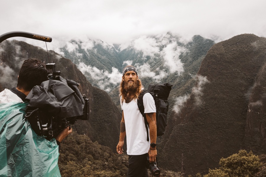 a man standing on top of a mountain next to a camera.