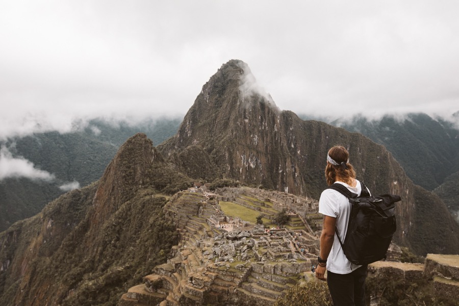 a woman standing on top of a mountain with a backpack.
