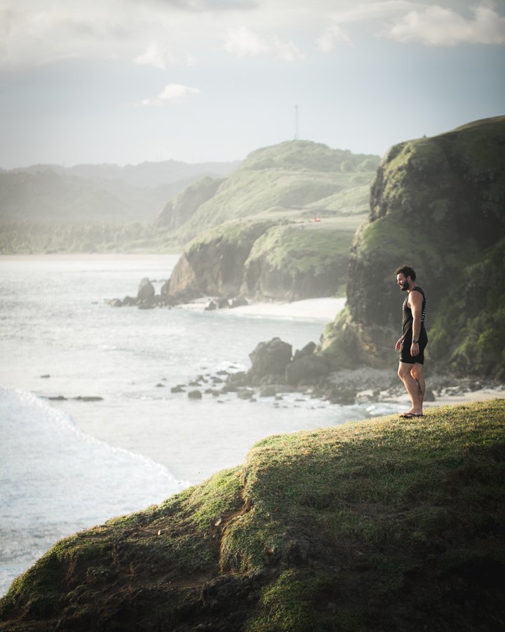 a woman standing on a hill overlooking the ocean.