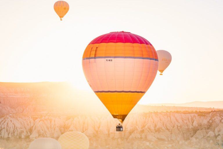 a couple of hot air balloons flying over a field.