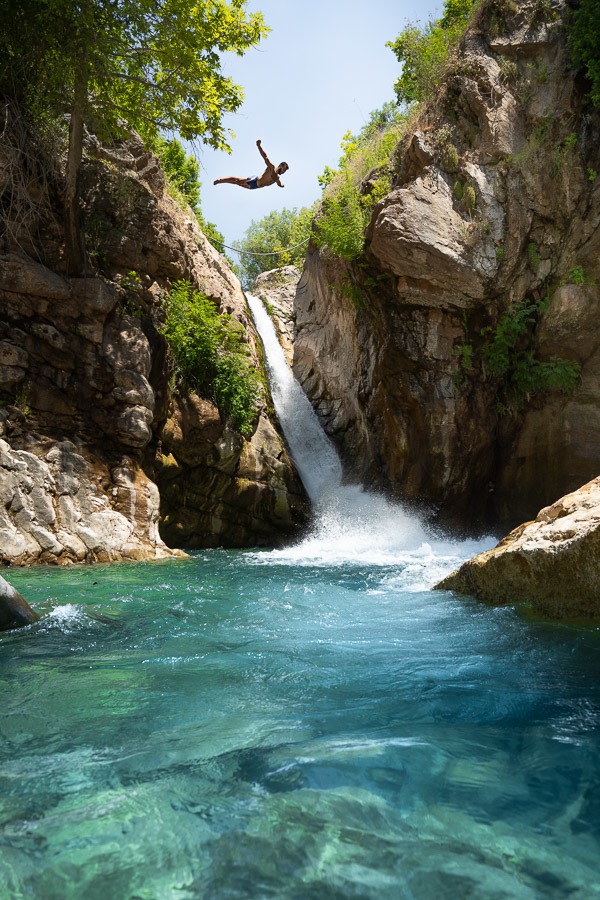 a person jumping off a cliff into a river.