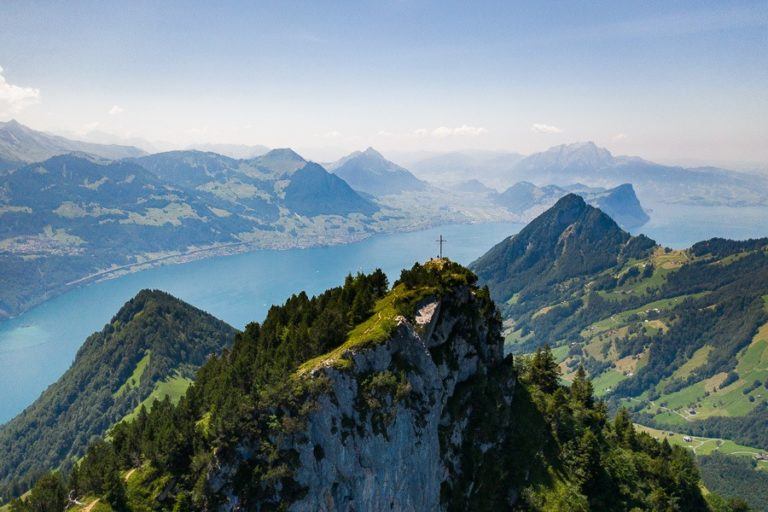 a view of a mountain with a lake and mountains in the background.