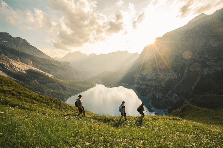a group of people walking up a hill next to a lake.