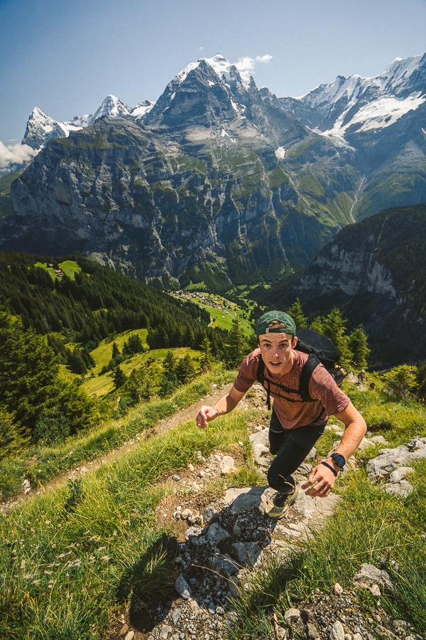 a man hiking up a steep hill in the mountains.