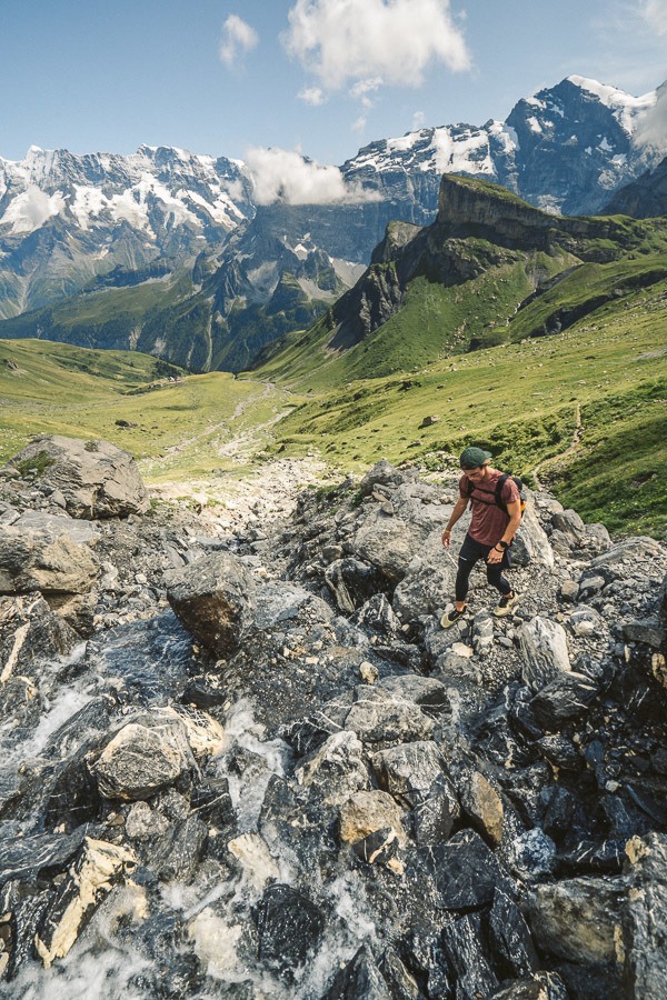a man hiking up a rocky trail in the mountains.