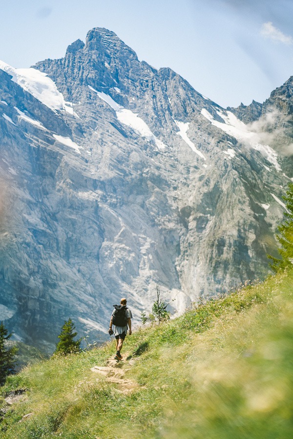 a person walking up a hill with a mountain in the background.