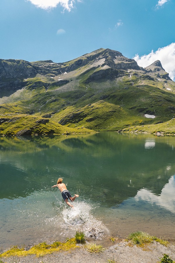 a man is swimming in a mountain lake.