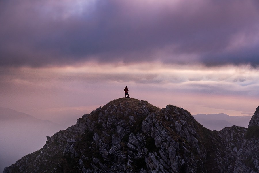a person standing on top of a mountain on a cloudy day.
