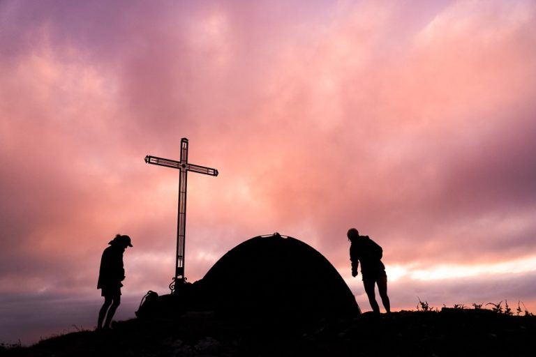 a couple of people standing next to a cross.