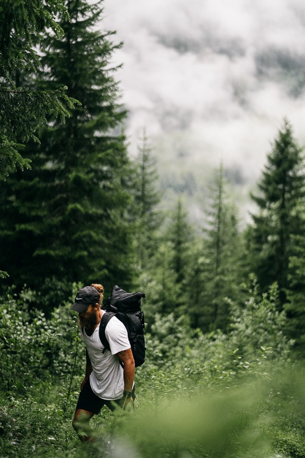 a man with a backpack walking through a forest.