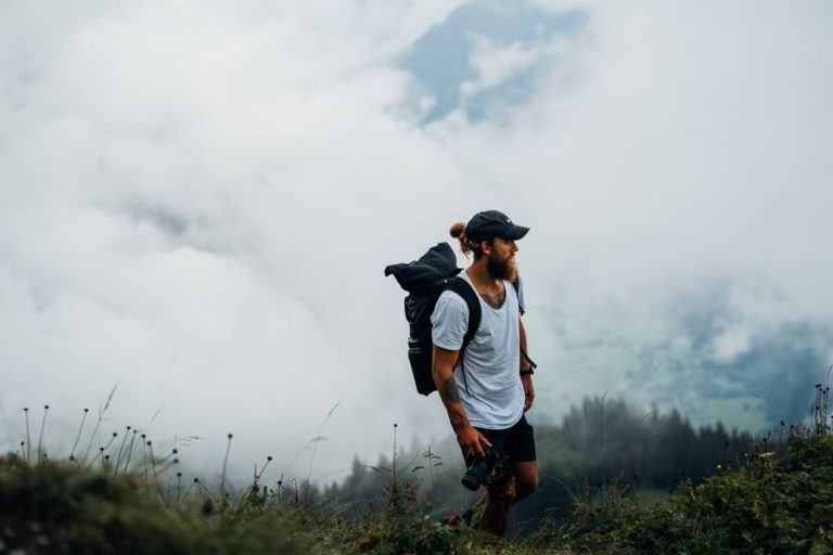 a man with a backpack standing on a hill.