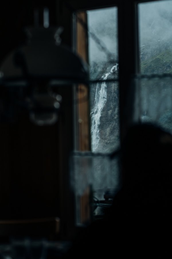 a person looking out a window at a waterfall.