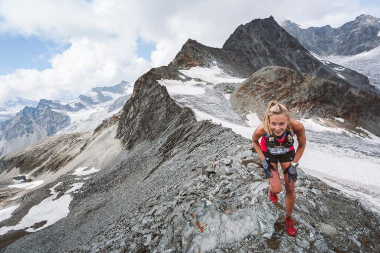 a woman hiking up a mountain on a cloudy day.