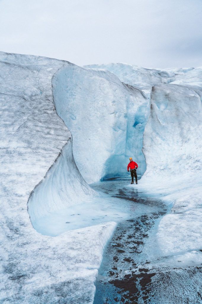 a man in a red jacket standing on a glacier.