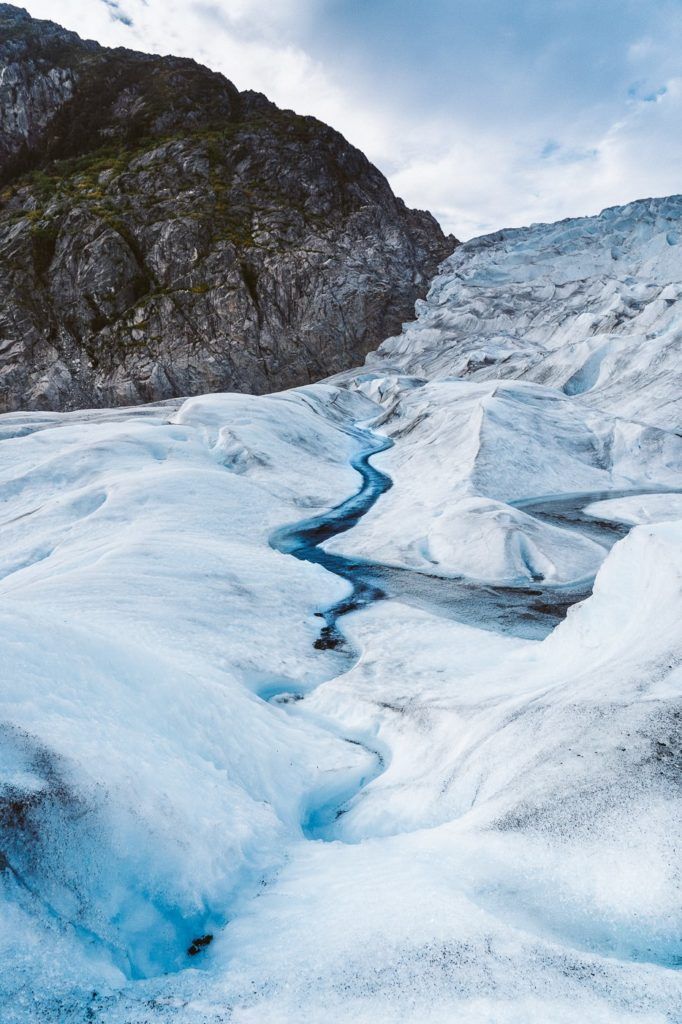 a small stream of water running through a glacier.