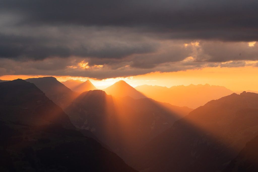 the sun shines through the clouds over the mountains.