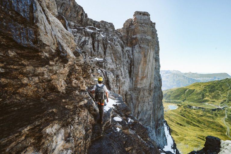 a group of people climbing up the side of a mountain.
