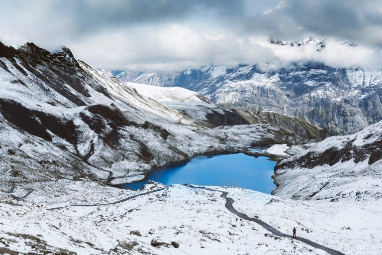 a blue lake surrounded by snow covered mountains.